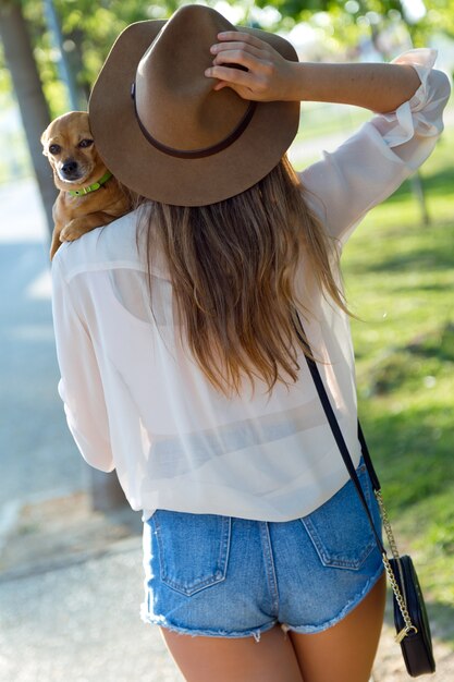 Beautiful young woman walking with her dog in the park.