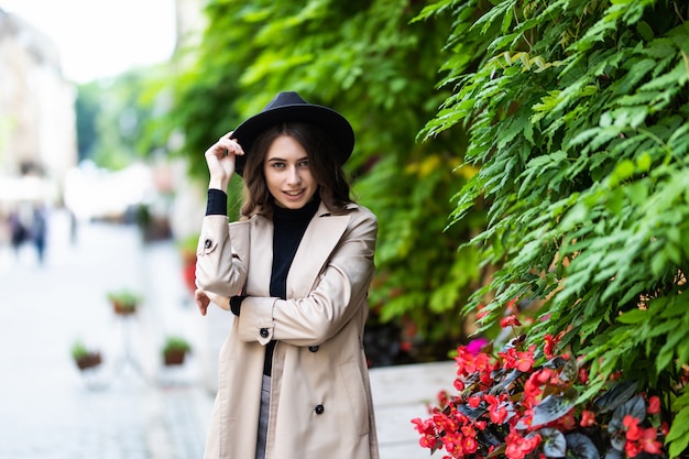 아름 다운 젊은 여자는 도시에서 걷는 모자와 코트에 착용.