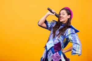 Free photo beautiful young woman wearing funky clothes and singing microphone. having fun