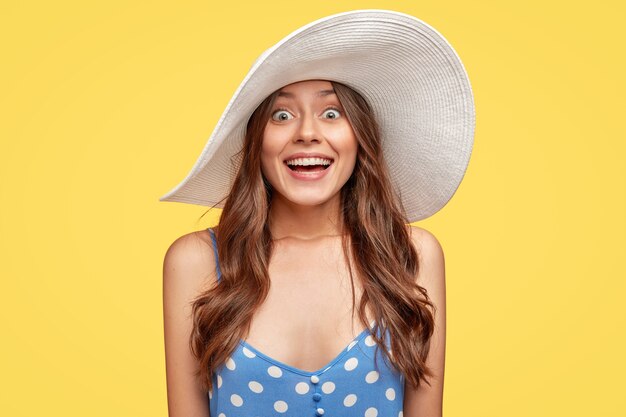 beautiful young woman wearing a hat posing against the yellow wall