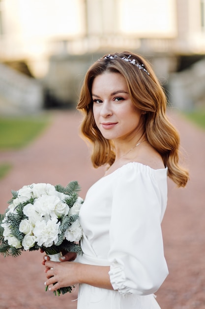 Beautiful young woman in wedding dress posing on the street in city