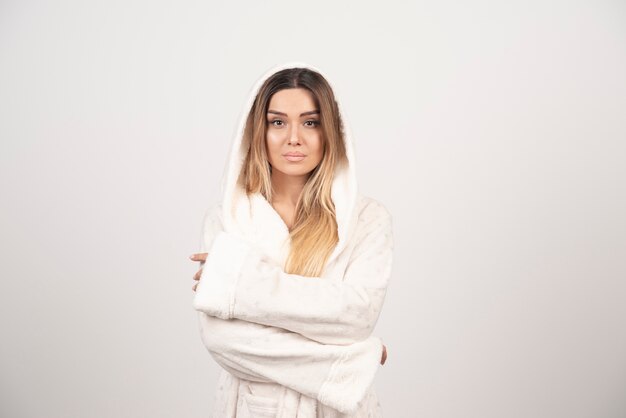 Beautiful young woman in a white bath robe isolated on white background .