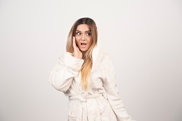 Beautiful young woman in a white bath robe isolated on white background .