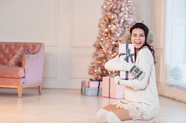 Beautiful young woman in a white dress throws up a gift