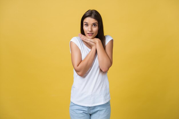 Beautiful young woman in white shirt is holding head in hands smiling and looking at camera