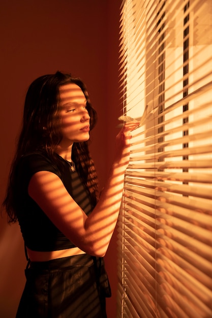 Beautiful young woman behind window blinds