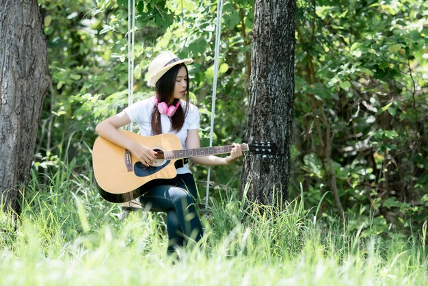 自然でAcusticギターを持つ美しい若い女性