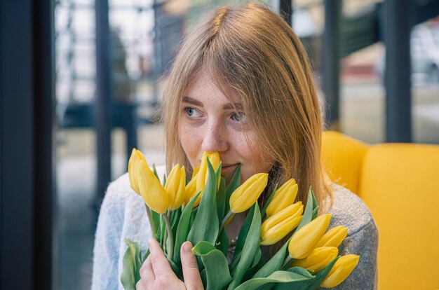 黄色いチューリップの花束を持つ美しい若い女性