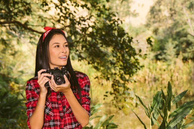 Beautiful young woman with camera looking away