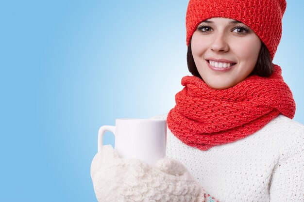 Beautiful young woman with charming smile and bright eyes wearing warm knitted winter clothes