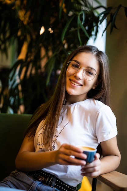 Bella giovane donna con una tazza di caffè in un bar