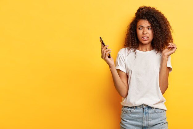 Beautiful young woman with curly hair posing with her phone