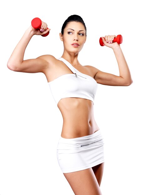beautiful young woman with dumbbells -  grey studio background. Healthy lifestyle concept.