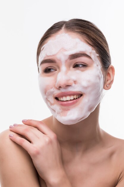 Beautiful young woman with facial mask on white wall