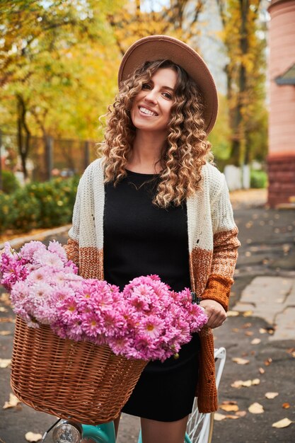 Beautiful young woman with flowers standing on the street
