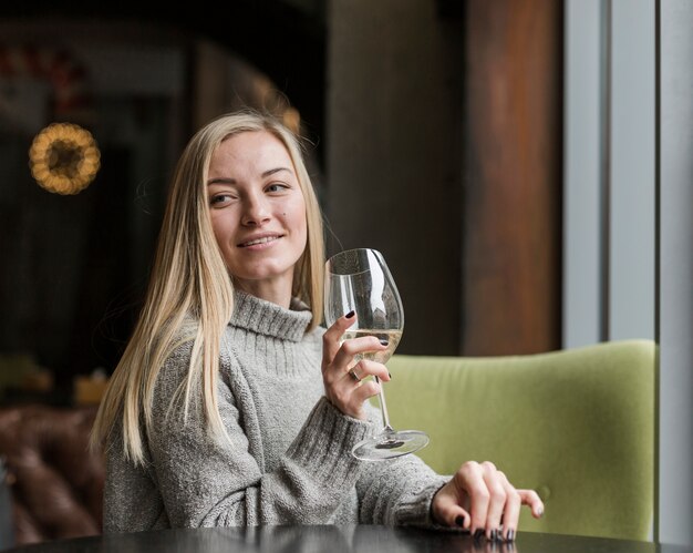 Beautiful young woman with glass of wine looking away