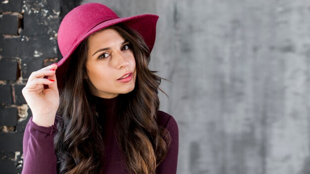 Beautiful young woman with hat on her head looking at camera