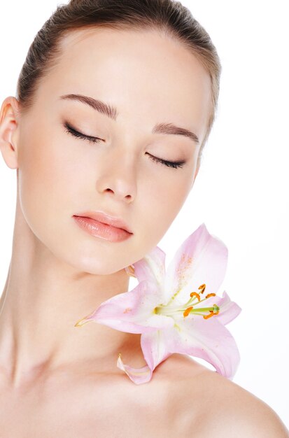 Beautiful young woman with health skin and flower on her shoulder
