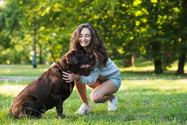 Bella giovane donna con il suo cane in giardino