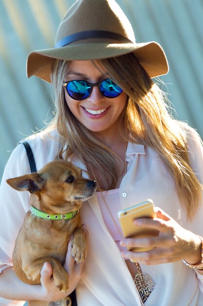 携帯電話を使用して彼女の犬と美しい若い女性。