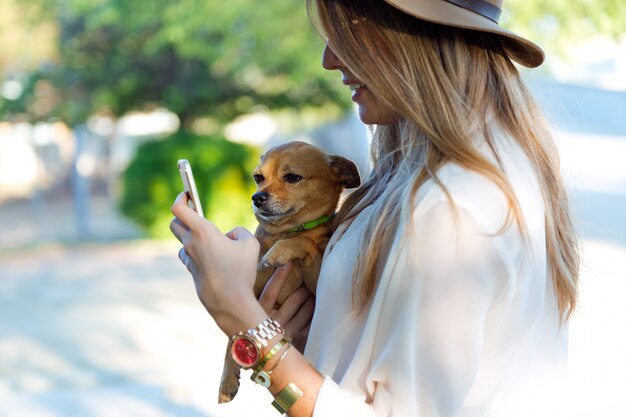 Beautiful young woman with her dog using mobile phone.