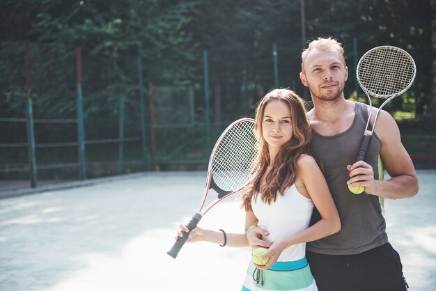 A beautiful young woman with her husband puts on an outdoor tennis court.