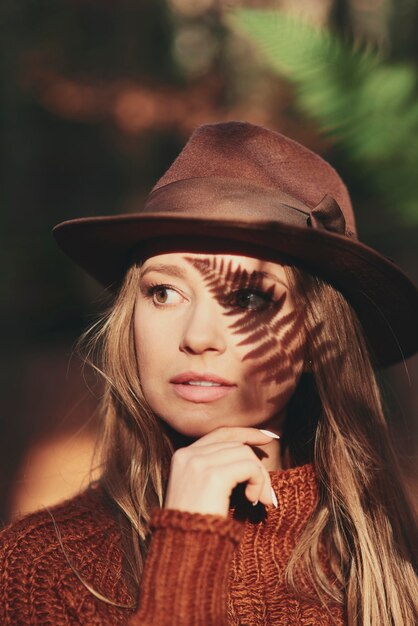 Beautiful young woman with leaf shadow on face