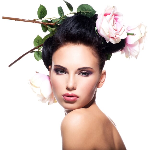 Beautiful young woman with pink flowers in hair - isolated on white.