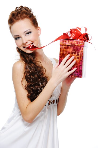 Beautiful young woman with a red box in her arms slightly bite ribbon and draw it