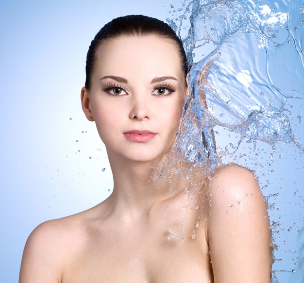 Beautiful young woman with splashes of water on her body- colored space