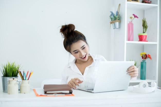 아름 다운 젊은 여자는 그녀의 방에 그녀의 노트북에서 작동합니다.