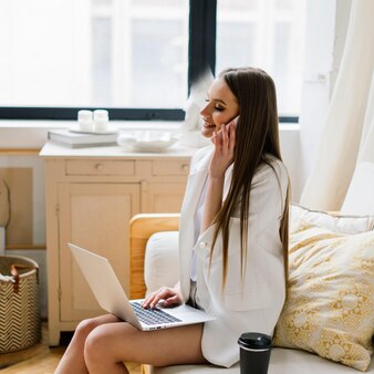 거실에 앉아 커피를 마시는 동안 노트북 컴퓨터 작업을 하는 아름다운 젊은 여성