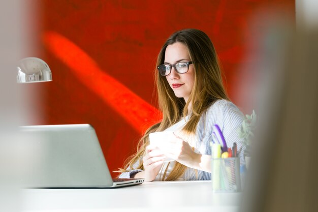Красивая молодая женщина, работающая с ноутбуком в своем офисе.