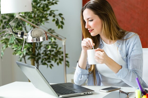 Beautiful young woman working with laptop in her office.