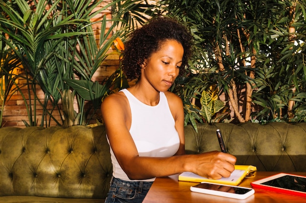 Beautiful young woman writing on diary over the wooden table