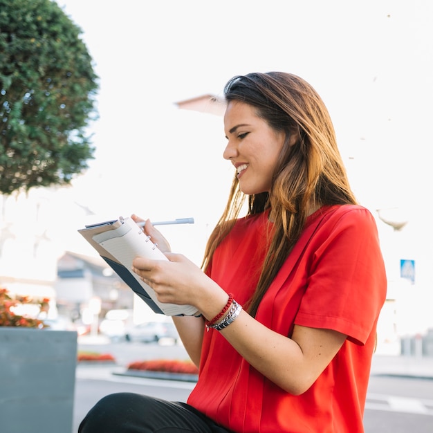 Beautiful young woman writing note in diary