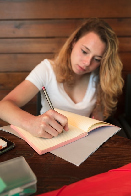 Foto gratuita bella scrittura della giovane donna in taccuino