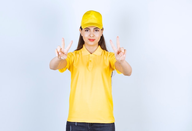 Beautiful young woman in yellow outfit giving signs on white background.