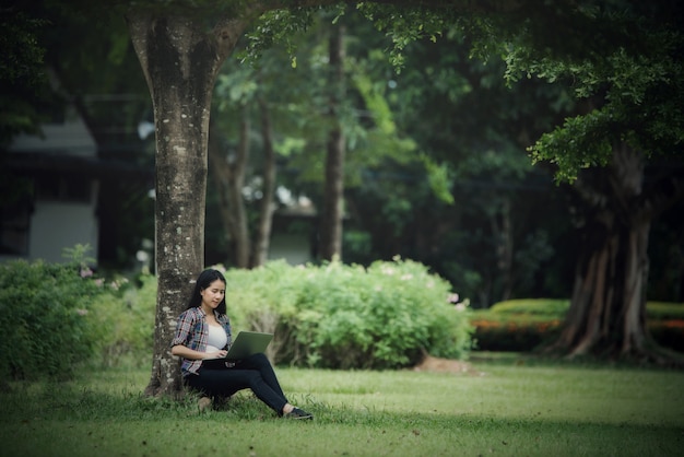 屋外の公園で本を読んで美しい若い女性