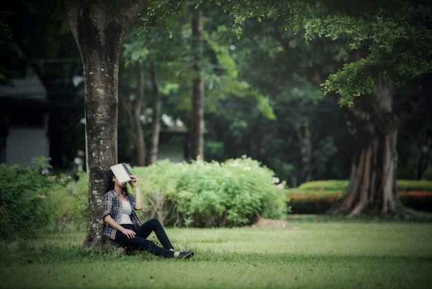 屋外の公園で本を読んで美しい若い女性