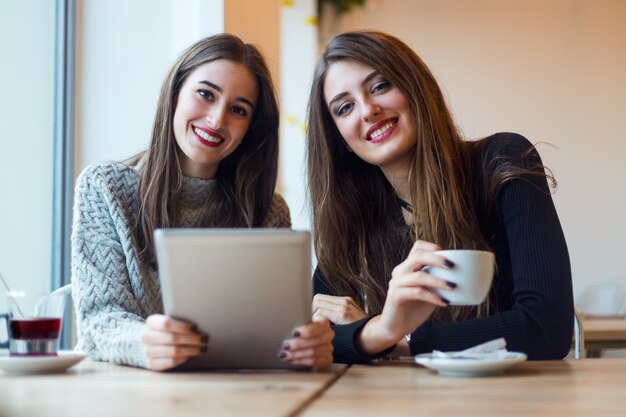 コーヒーショップでデジタルタブレットを使用している美しい若い女性。