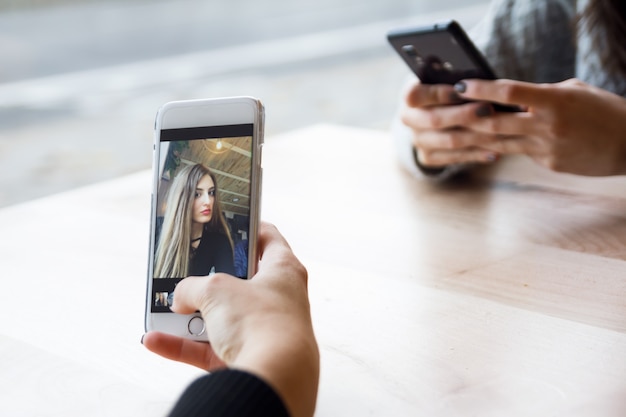 Foto gratuita bella giovane donna che utilizza il suo cellulare in caffè.