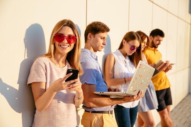 Beautifull woman in pink sunglasses smiling at camera and using mobile phone.