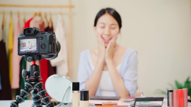 美しさのブロガーは、ビデオを録画するために正面のカメラに座っている美しさ化粧品を提示します。