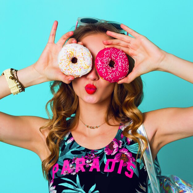 Девушка фотомодели красоты белокурая принимая красочные розовые donuts. Смешная радостная женщина с конфетами, десерт. Диета, диета концепции. Фастфуд. Яркие цвета.