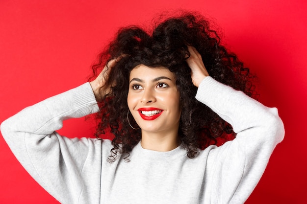 Beauty closeup portrait of carefree woman touching her curly hair and looking happy aside at logo sm...