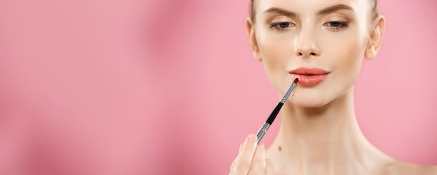 Free photo beauty concept happy fashion caucasian woman with long hair and red lips posing over pink studio background