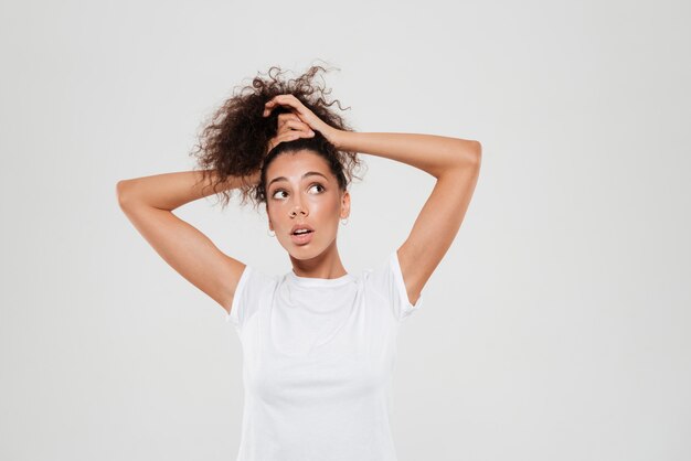 Beauty curly woman binds her hair in studio