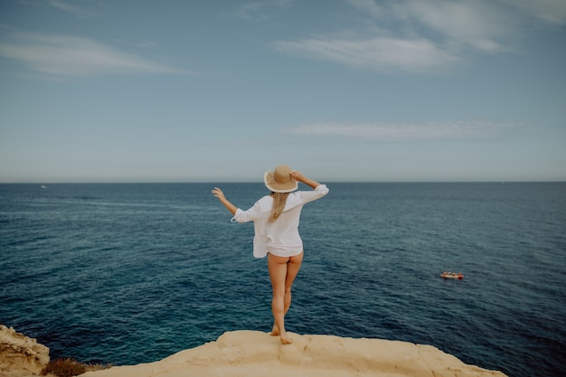 Foto gratuita ragazza carina di bellezza su un puntello di oceano mare spiaggia tropicale con grandi pietre.