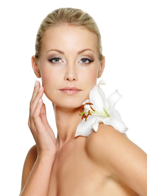 Beauty face of the young beautiful woman with flower. Female touching skin. Girl on white space